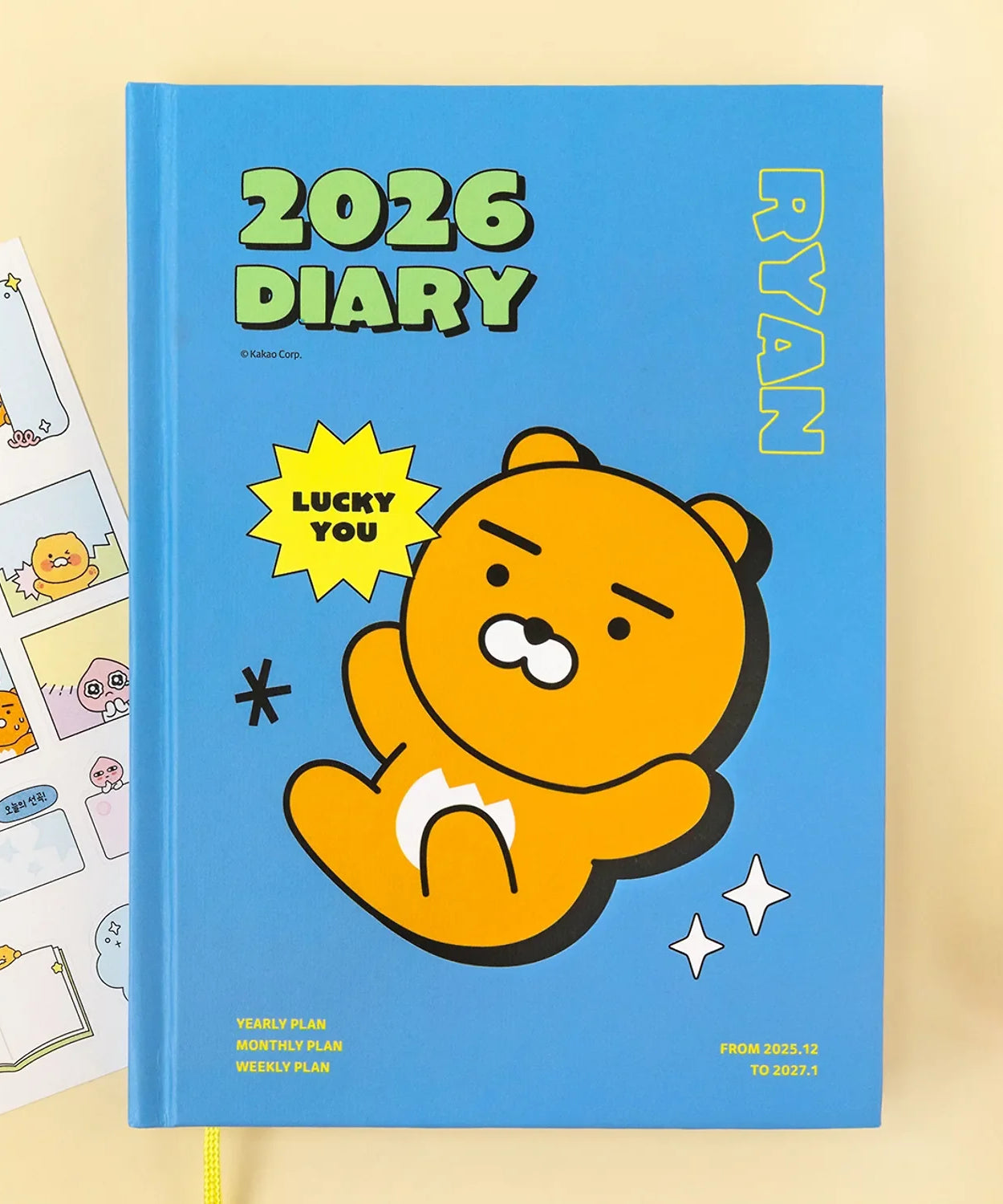 KAKAO FRIENDS Planner 2026 featuring Ryan character on blue cover with stickers, surrounded by stationery items.