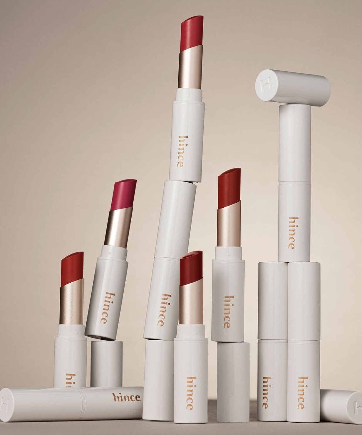 HINCE Mood Enhancer Lip Glow lipsticks in various shades, elegantly stacked with sleek packaging, showcasing vibrant color options.