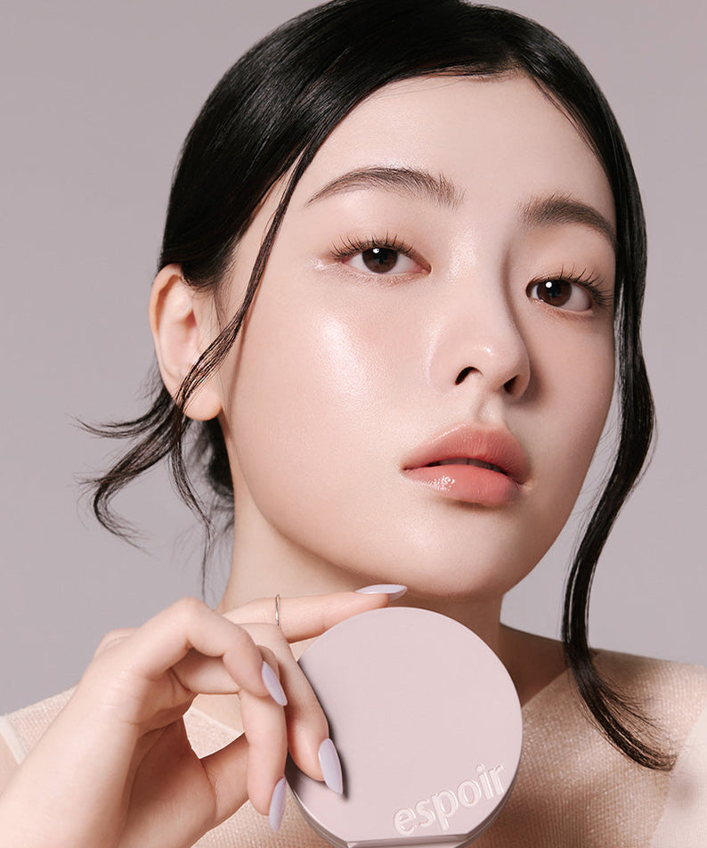 Woman holding ESPOIR Be Natural Cushion SPF50+ PA++++ showcasing radiant skin