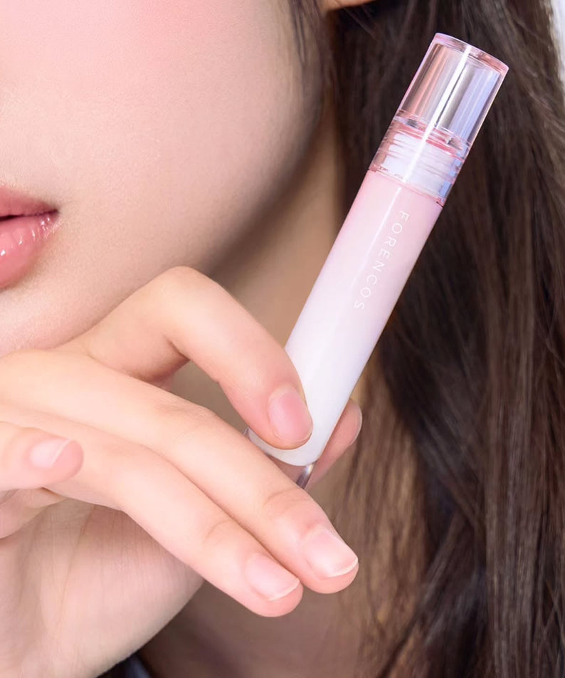 Close-up of a person holding FORENCOS All Light Mood Glow Tint next to their lips, showcasing the product design and color.