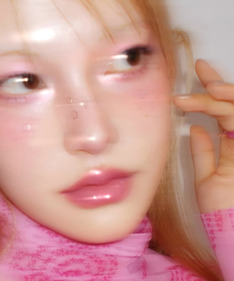 Close-up of a person wearing pink makeup, showcasing a glossy and ethereal look with FWEE Glitz Stone Highlighter.