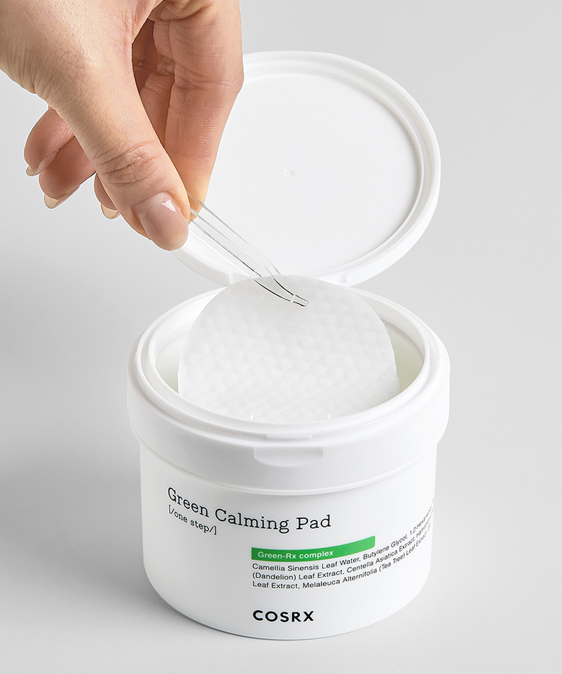 Hand holding a COSRX Green Calming Pad 140ml above the container