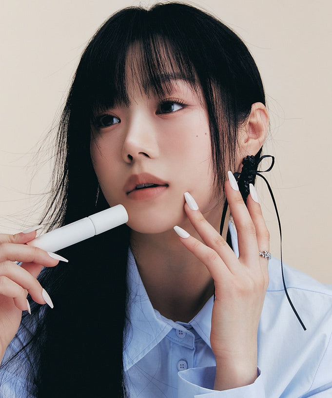 Person holding HEART PERCENT Dot On Mood All Cover Lip Base, emphasizing the product's sleek design and application style.