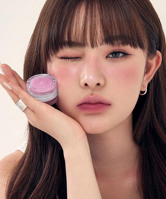 Woman holding HEART PERCENT Dot On Mood Custom Lip & Cheek, showcasing lip and cheek color in a stylish setting.