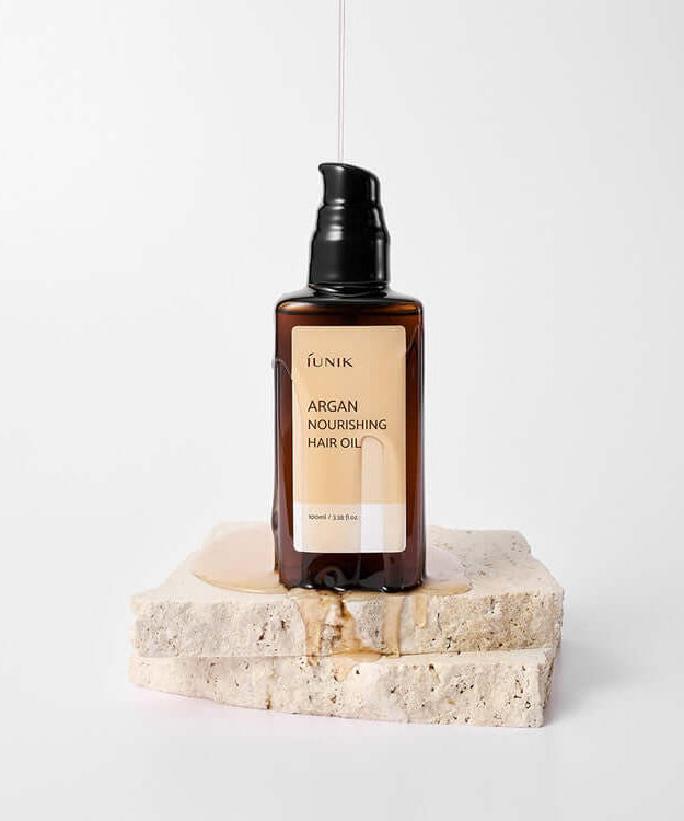 iUNIK Argan Nourishing Hair Oil 100ml bottle on a stone base for hair care