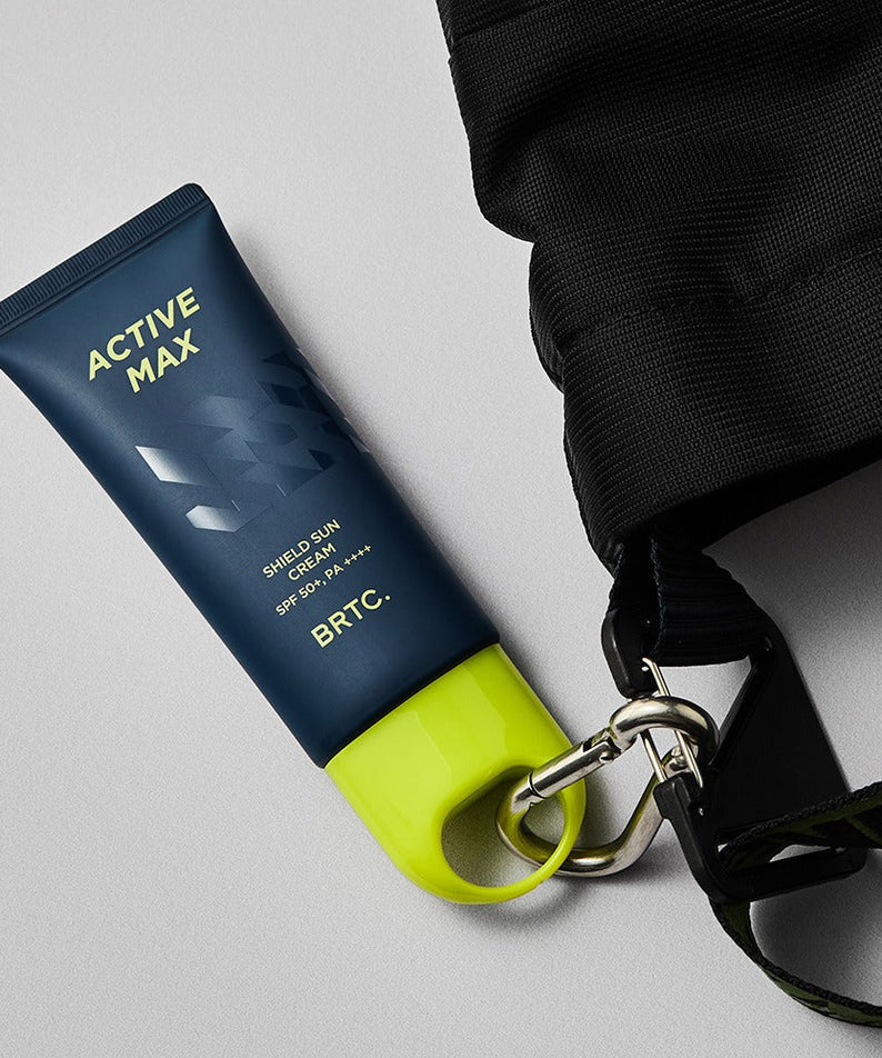 BRTC Homme Active Max Sheild Sunscreen 50ml - Gentleman Korea product image of navy tube with lime cap clipped to a black bag