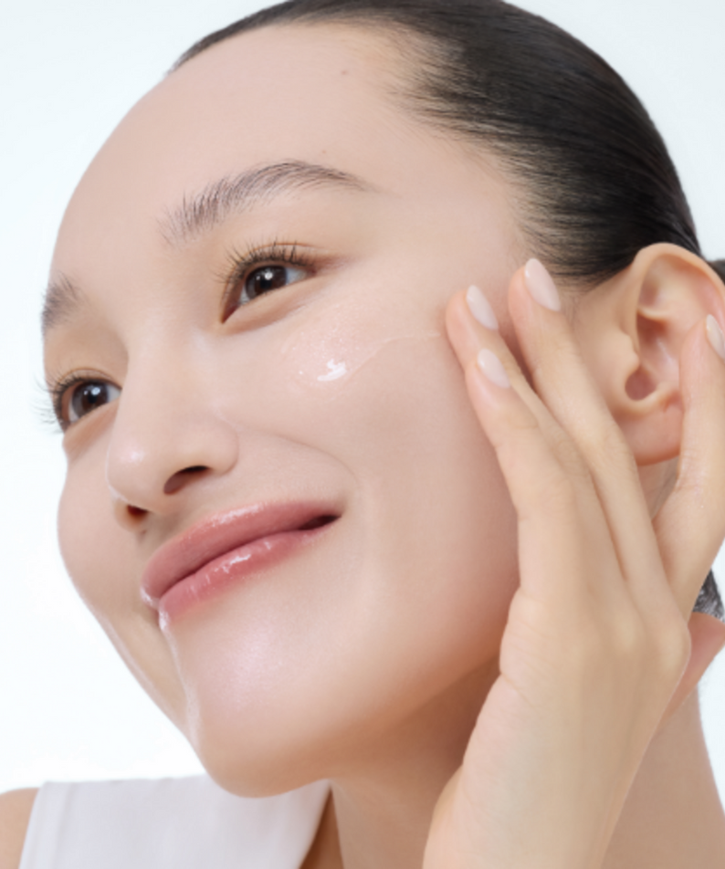 Woman applying skincare, smiling, healthy skin, moisturizing, beauty routine.