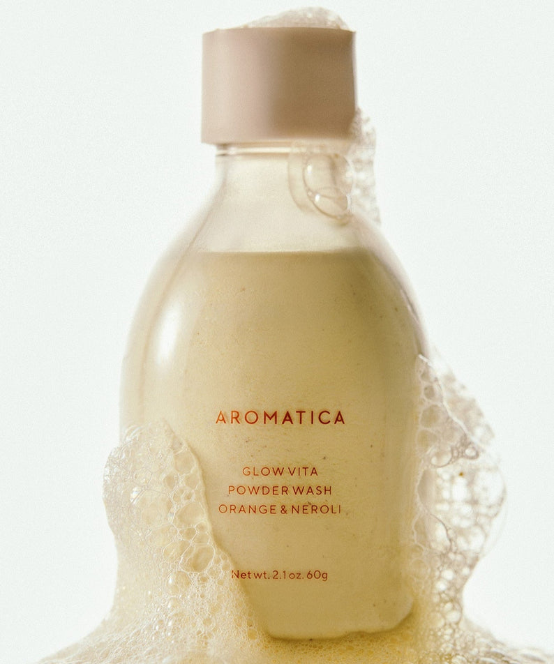 AROMATICA Glow Vita Powder Wash Orange & Neroli 60G with foaming bubbles in a bottle.