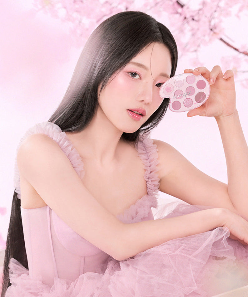 Model holding DASIQUE Pink Blossom Shadow Palette in front of cherry blossom background.