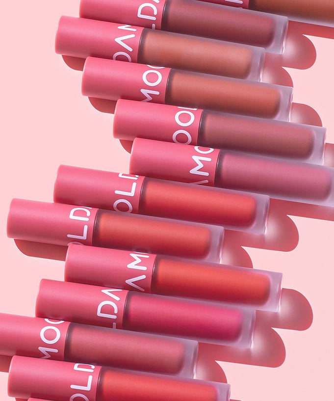 MOOLDA Tattoo Fixing Lip Tint collection in various shades displayed against a pink background, showcasing vibrant lip colors.