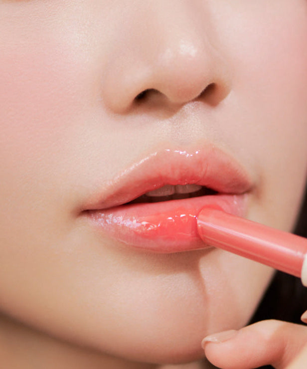 Close-up of a person applying pink lipstick, highlighting lip care and beauty.