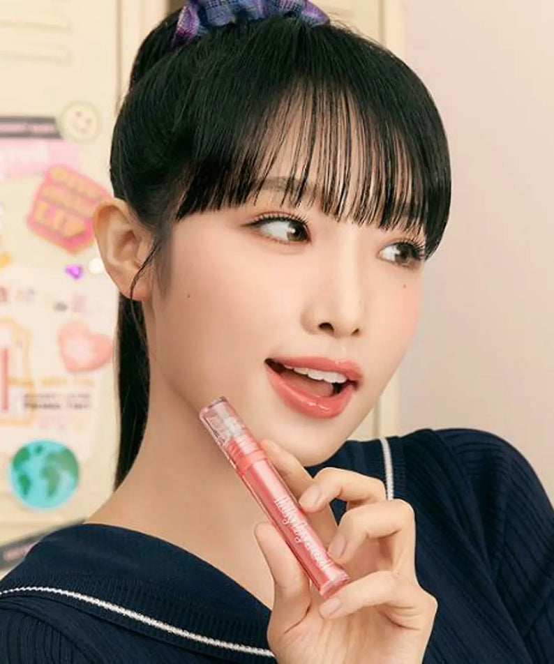 Young woman applying LILYBYRED Glassy Layer Fixing Tint with a stylish hairstyle.