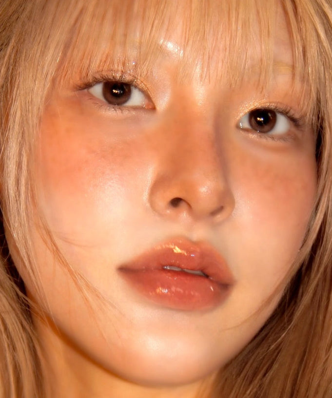 Model wearing UNLEASHIA Sunset Dazzle Gloss Balm with a luminous glow.