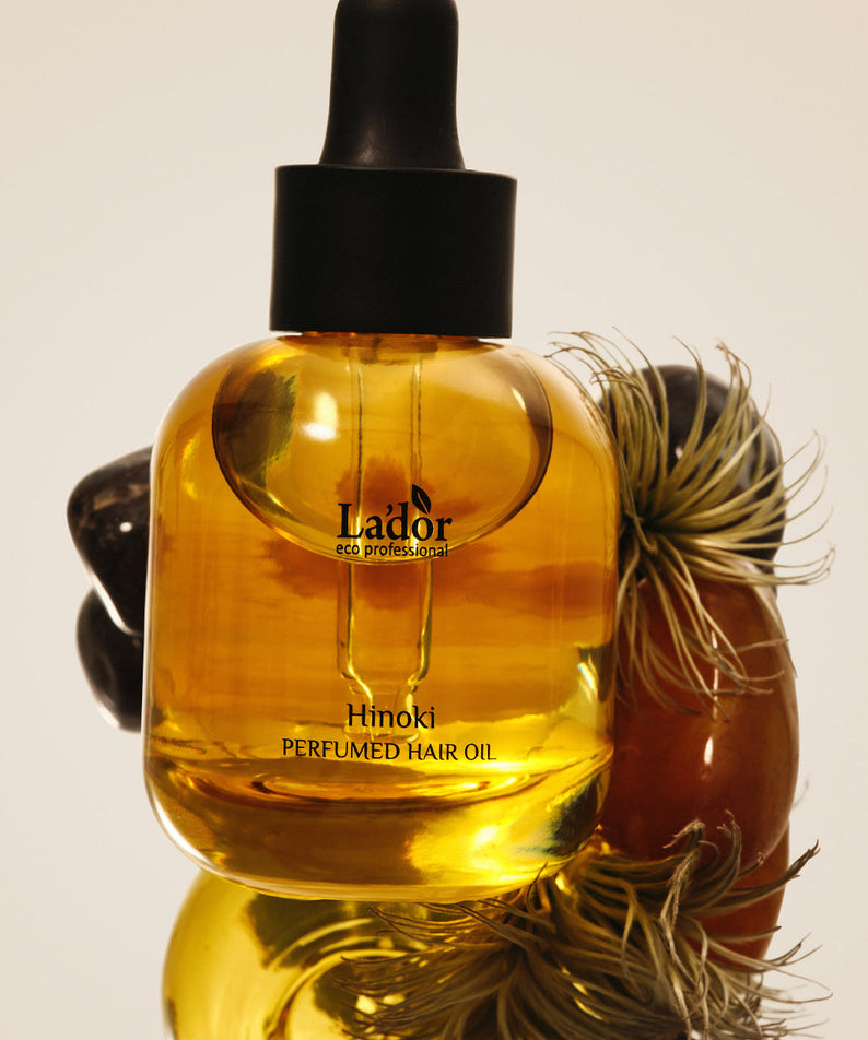 LADOR Perfume Hair Oil 30ml bottle on display with decorative elements, showcasing premium hair care product.