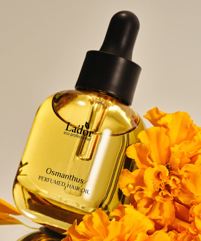 LADOR Perfume Hair Oil 30ml bottle with orange flowers, enhancing hair fragrance and shine, against a neutral background.