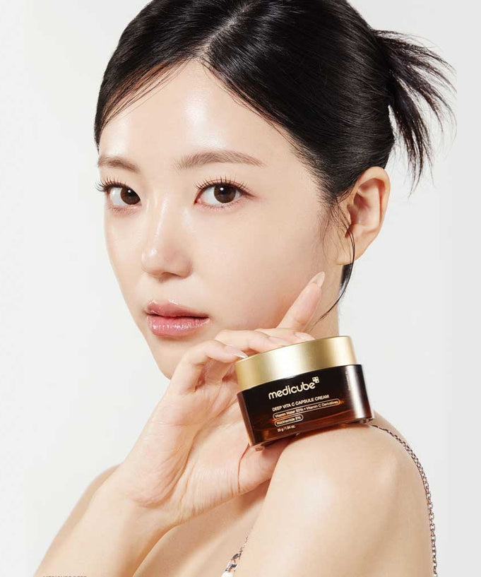 Woman holding MEDICUBE Deep Vita C Capsule Cream 55g, showcasing the product's packaging.