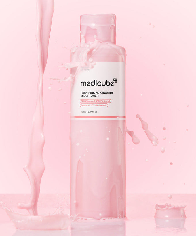 Bottle of MEDICUBE PDRN Milky Toner Essence 150ml with pink liquid splash on a pink background