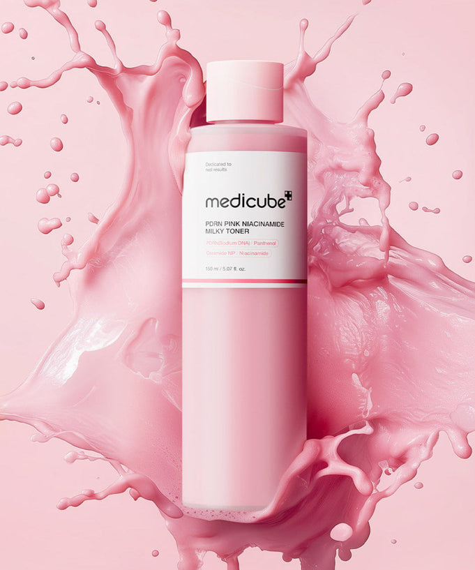 MEDICUBE PDRN Milky Toner Essence 150ml bottle on pink splash background showcasing skincare product packaging.