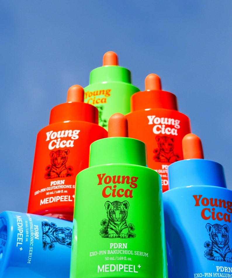 Five colorful bottles of MEDIPEEL Young Cica PDRNExo-Pin Hyaluronic Serum 50ml stacked against a clear blue sky.