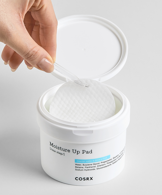 Hand using COSRX Moisture Up Pad 140ml for skincare, showing open container and texture of pads.