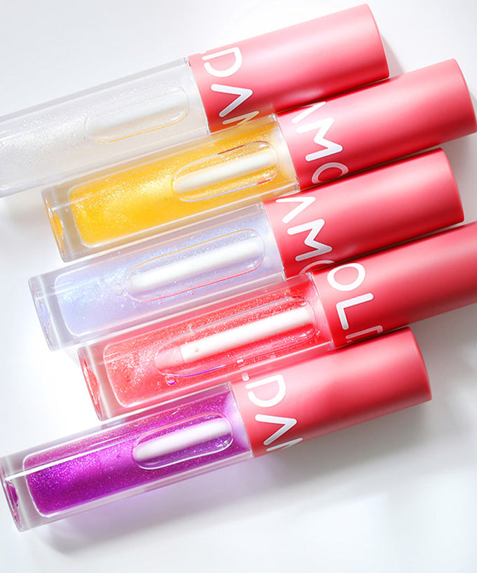 Colorful tubes of MOOLDA Volume Maxima Lip Plumper displayed in a flat lay arrangement.