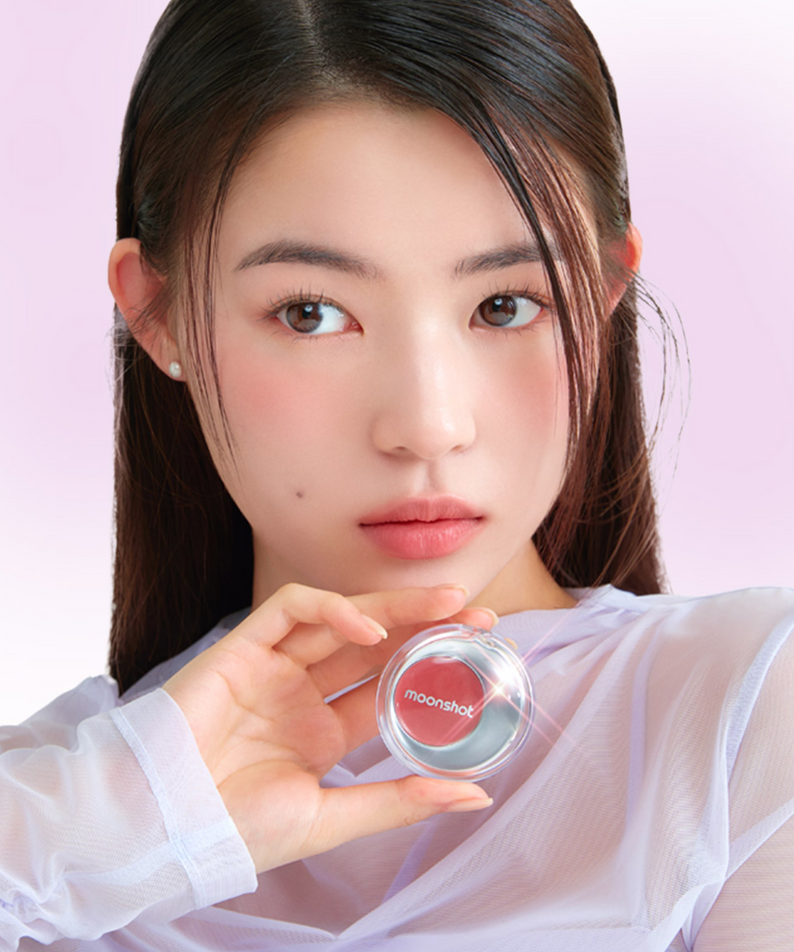 Person holding MOONSHOT Melting Mood Lip & Cheek product, showcasing vibrant lip and cheek color in a stylish packaging