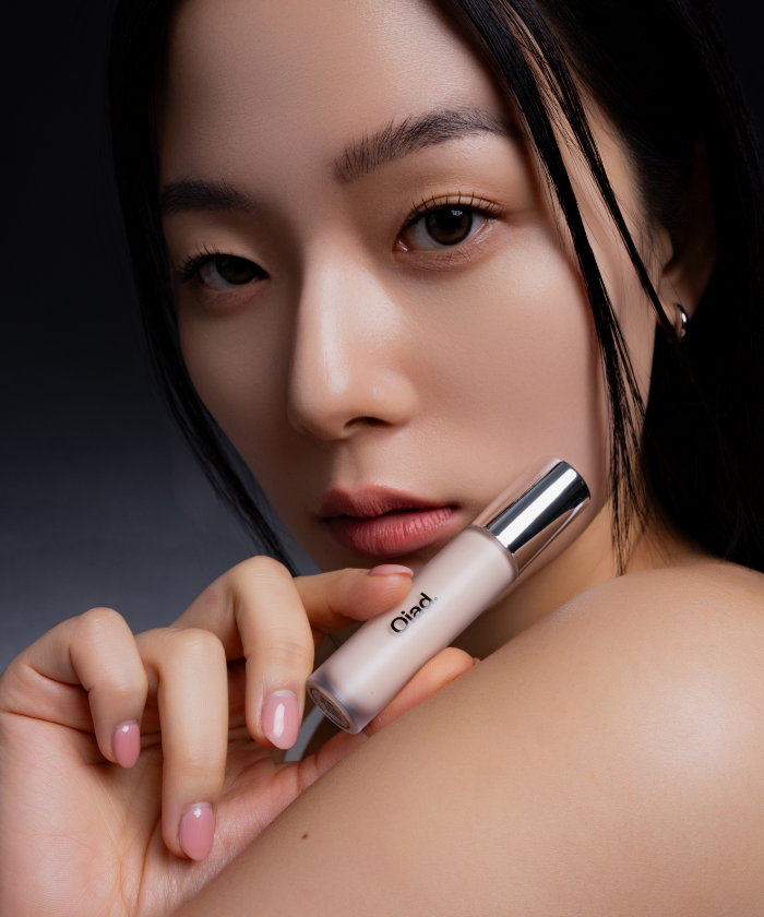 Woman holding OIAD Cover Perfecting Mirror Brushed Concealer showcasing flawless skin results