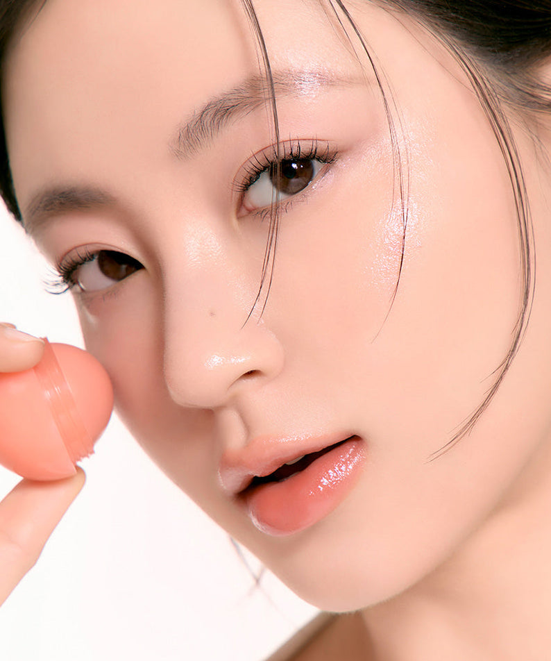 Woman applying ROMAND Juicy roll cheek blush for a fresh look