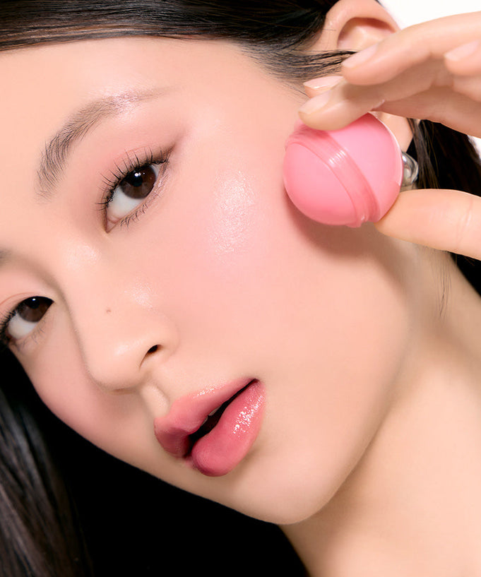Woman applying ROMAND Juicy roll cheek blush for a fresh, glowing look.