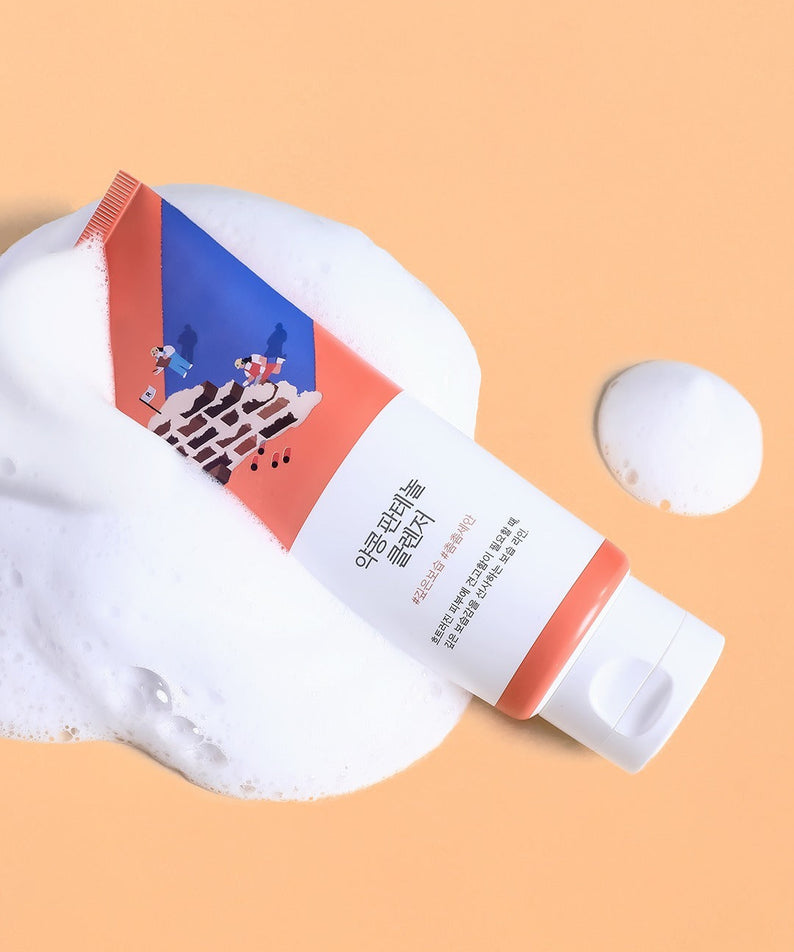 ROUNDLAB Yakkong Panthenol Cleanser 150ml on peach background with foam, skincare product packaging.