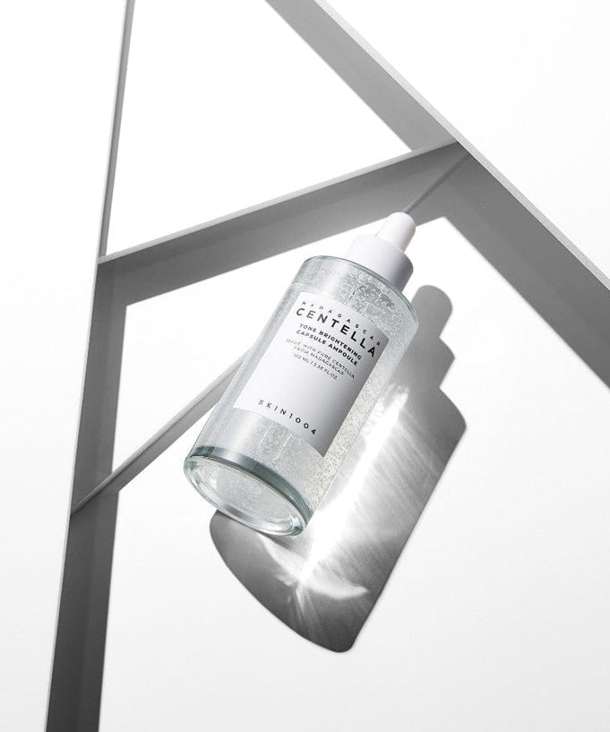 Bottle of SKIN1004 Madagascar Centella Tone Brightening Capsule Ampoule 100ml placed on geometric white background with shadow