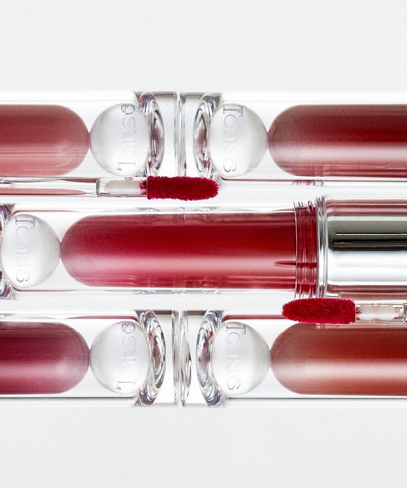 TENSE Shine Moment Glossy Tint in various shades and sleek packaging displayed on a white background.