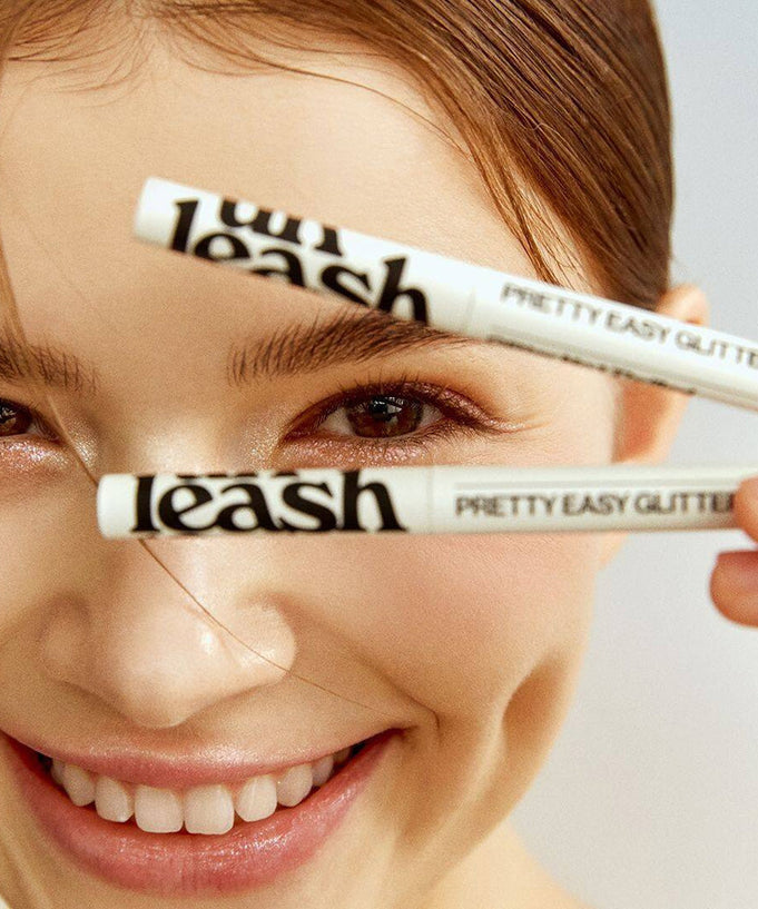 UNLEASHIA Pretty Easy Glitter Stick held by a smiling person showcasing the product's sleek design and glitter application.