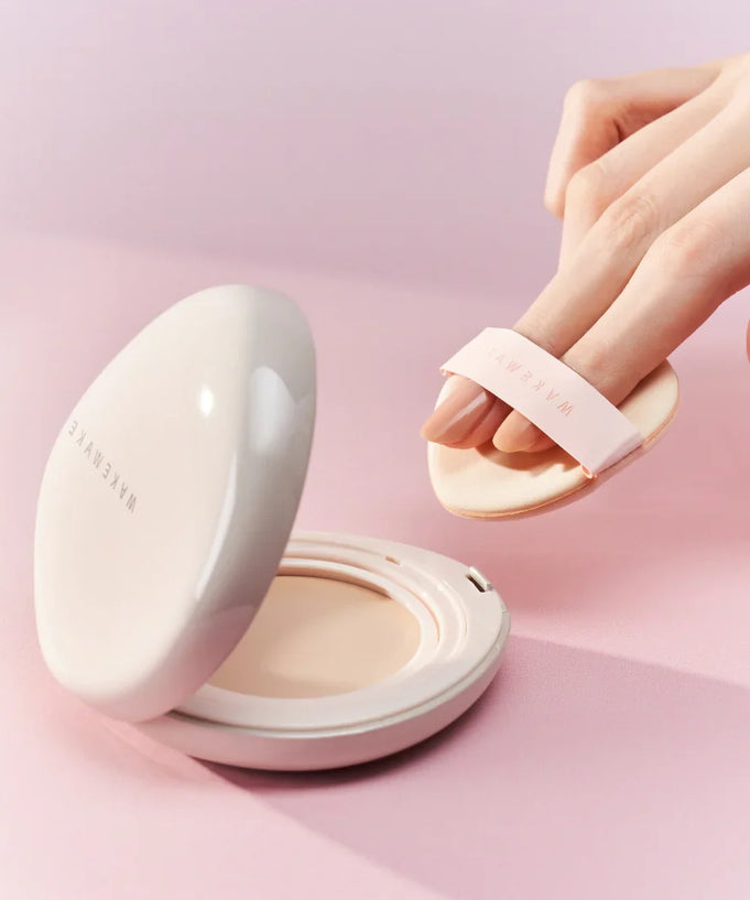 Person applying WAKE MAKE Water Glow Coating Balm 12.5g with a makeup applicator on a pink background