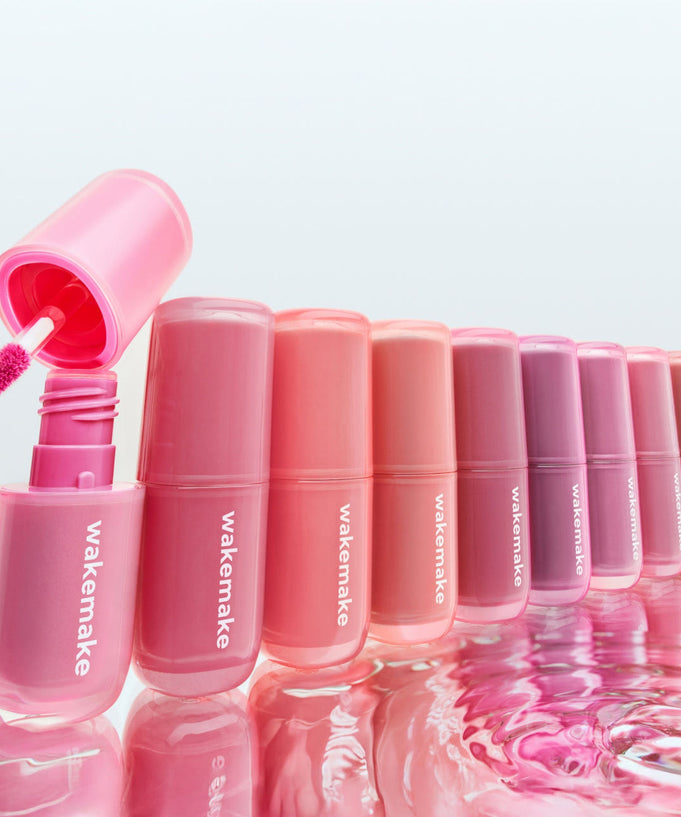Colorful lineup of WAKE MAKE Waterfull Glow Tint 4.6g bottles displaying vibrant shades and an open applicator on the left.